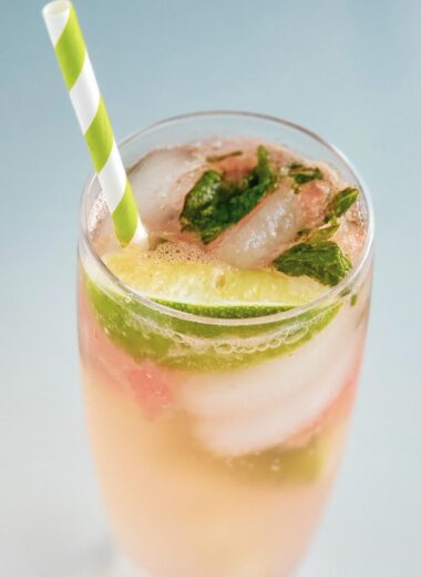cocktail glass with watermelon mojito, ice, lime, mint, and a green and white striped straw