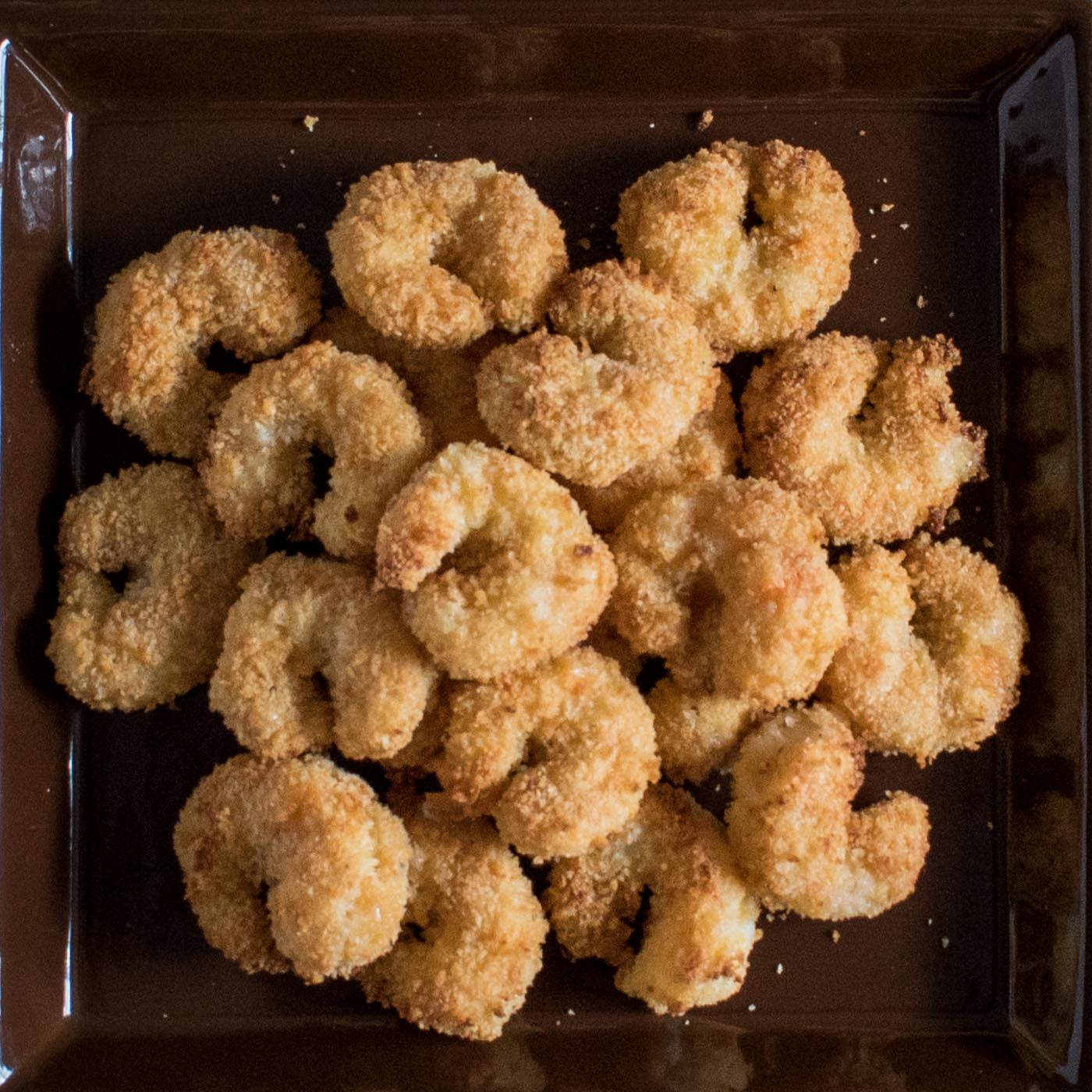 brown square plate piled with golden fried shrimp