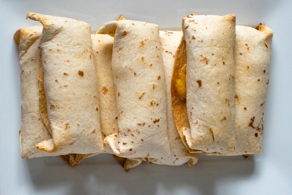 top down view of a stack of rolled burritos on a white plate