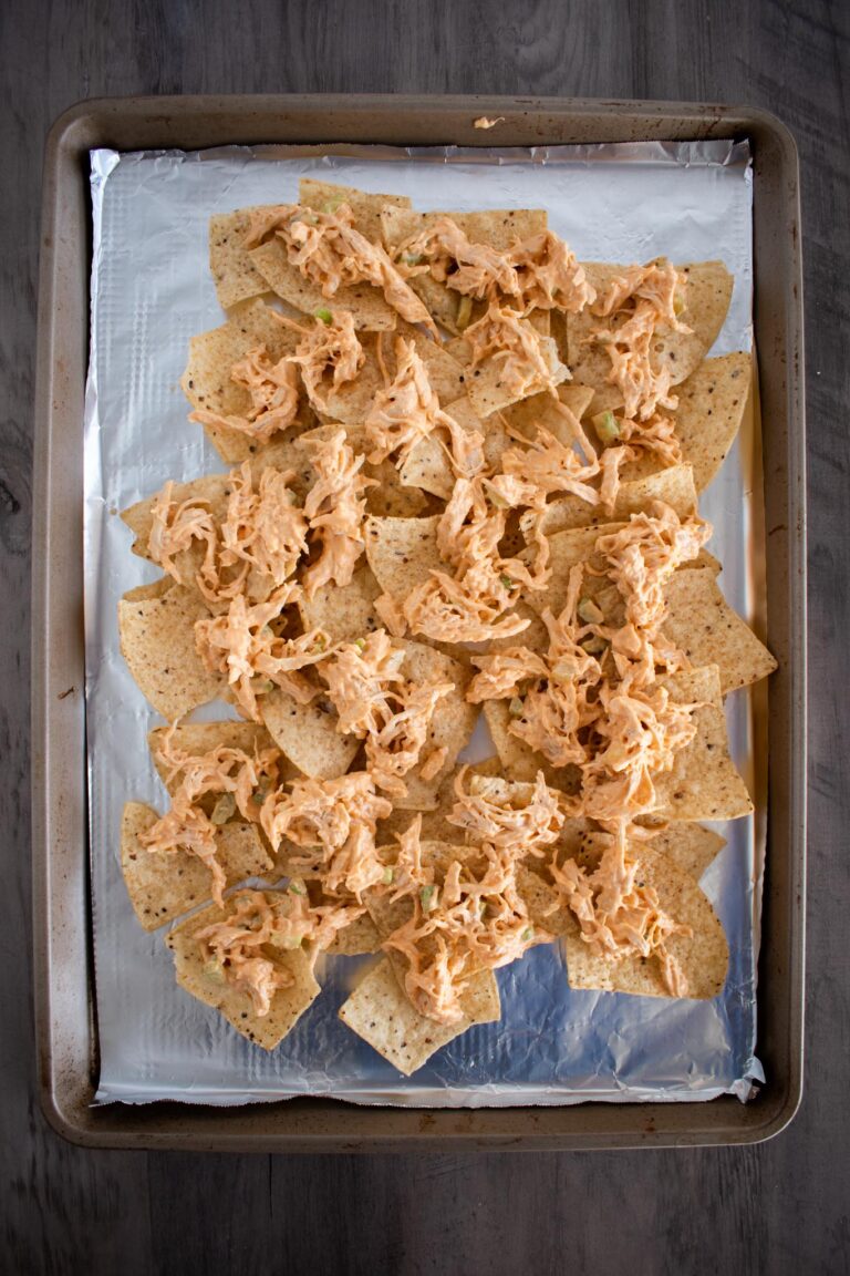 sheet pan lined with  aluminum foil and a layer of chips and shredded buffalo chicken.