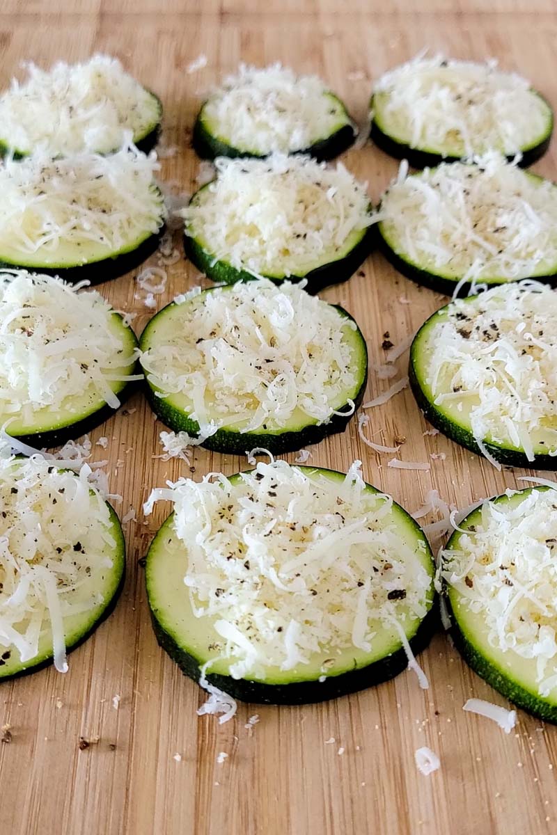 zoomed in zucchini rounds with grated parmesan cheese on top of each slice.