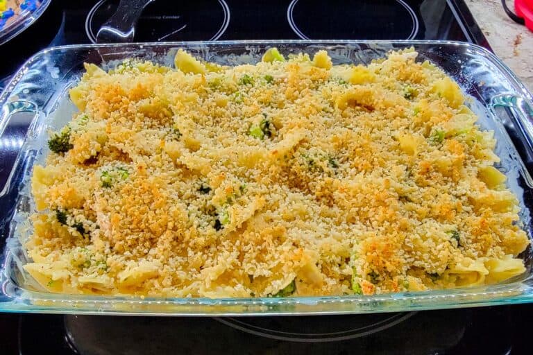 glass casserole dish with baked chicken broccoli alfredo casserole and golden breadcrumb topping.
