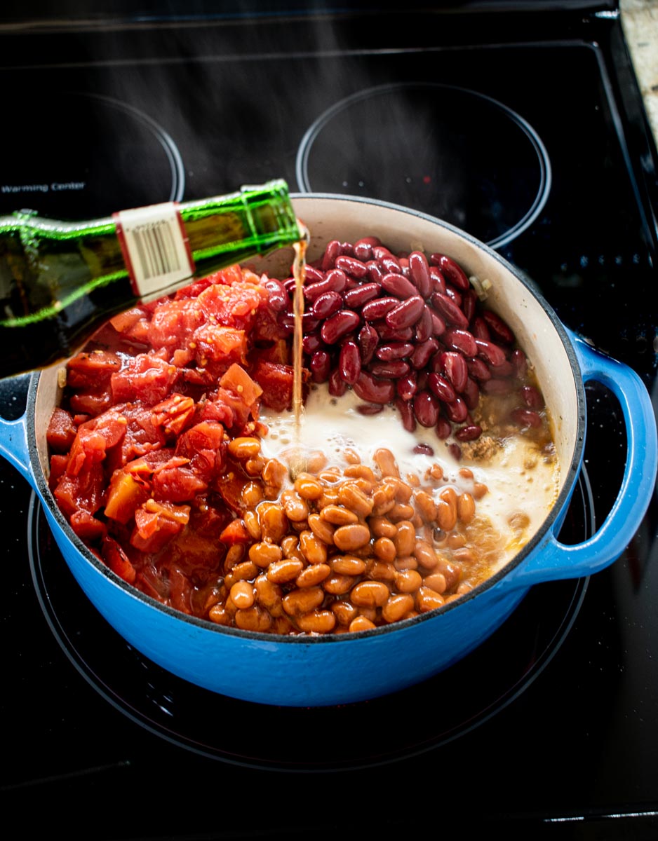 pouring beer into pot of all other chili ingredients.