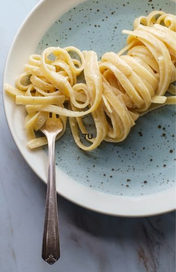 long twirl of fettuccini noodles on a plate with a fork.